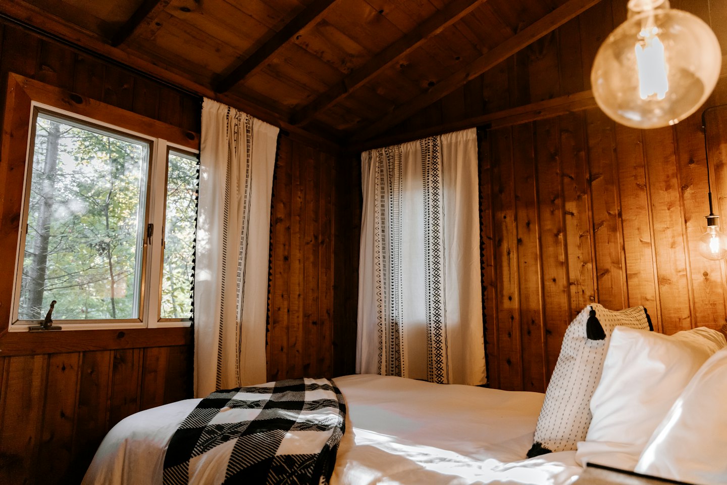 Dormitorio de madera con una cama que tiene una manta a cuadros.