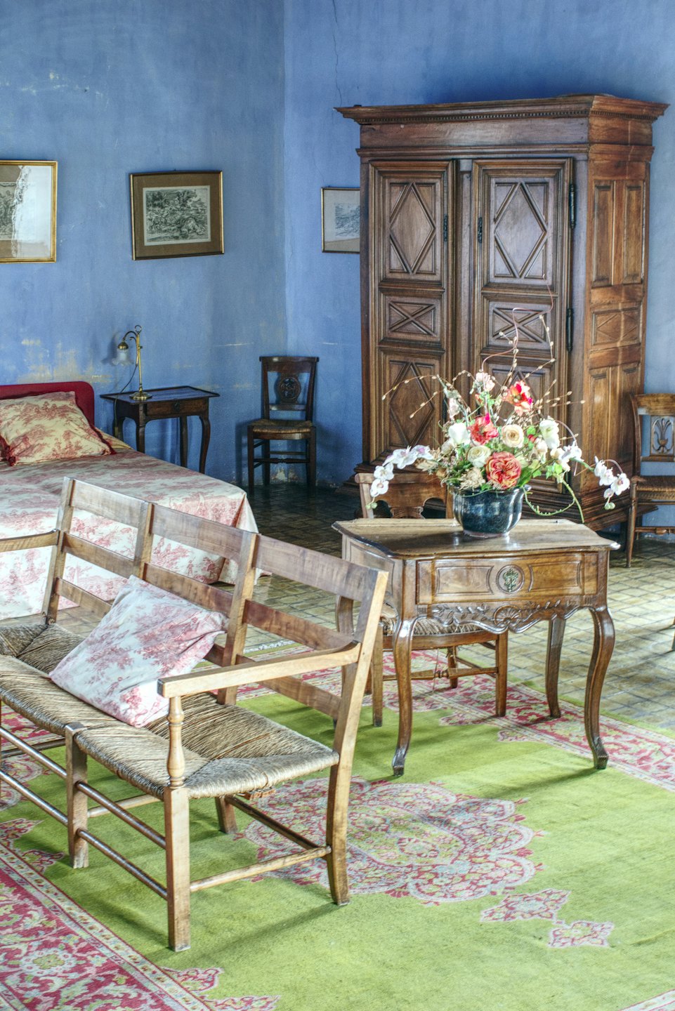 Dormitorio tradicional con muebles antiguos y ropa de cama de toalla roja.