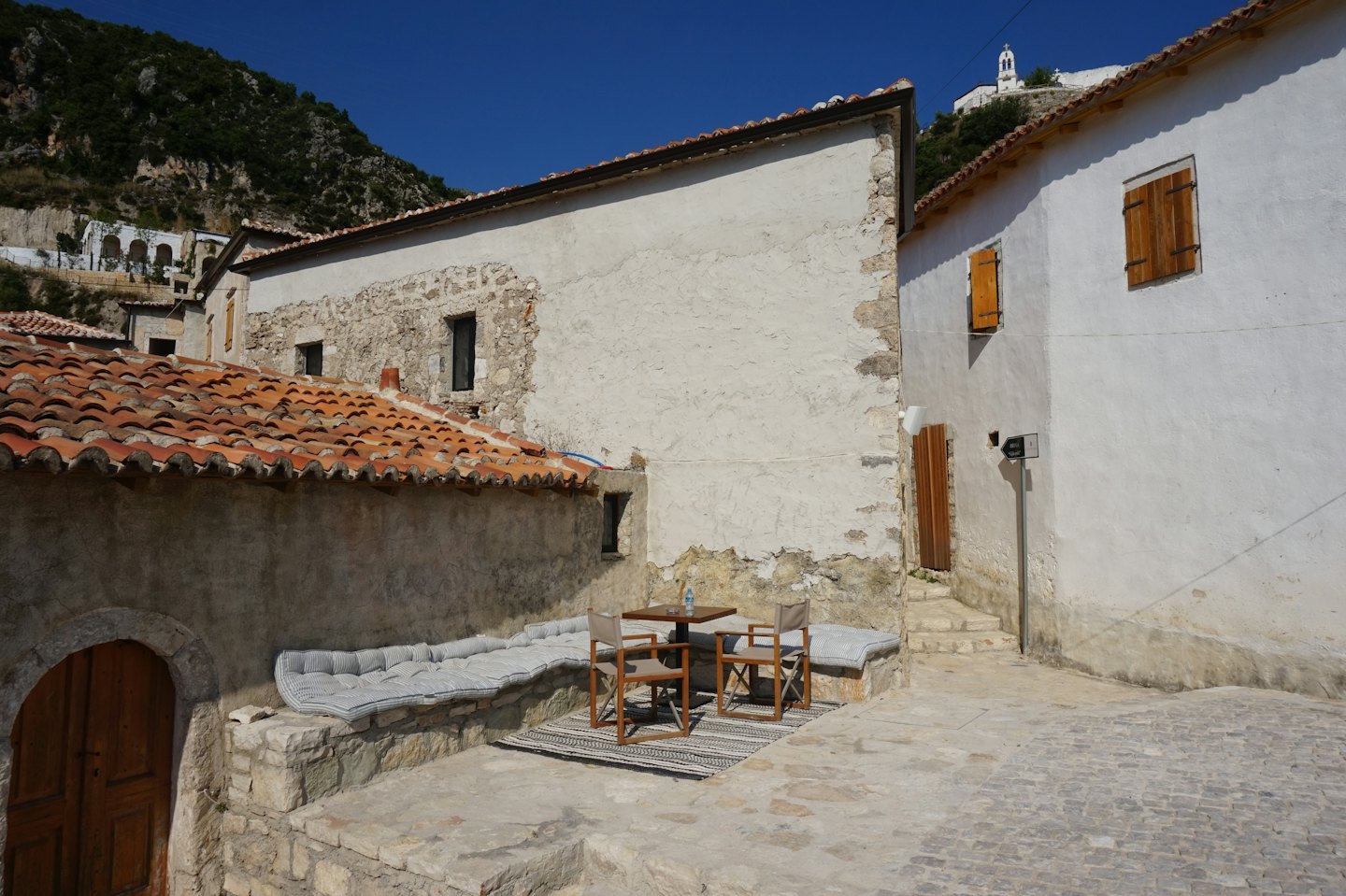 Mesa y sillas de madera en un patio de piedra.